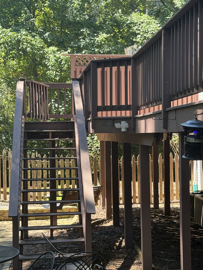 The wooden stairs coming down from the deck to the patio, with no lighting on them